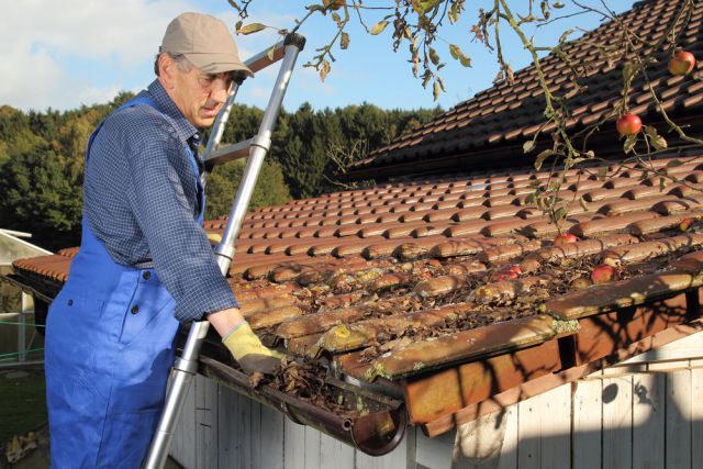 Old man cleaning gutters